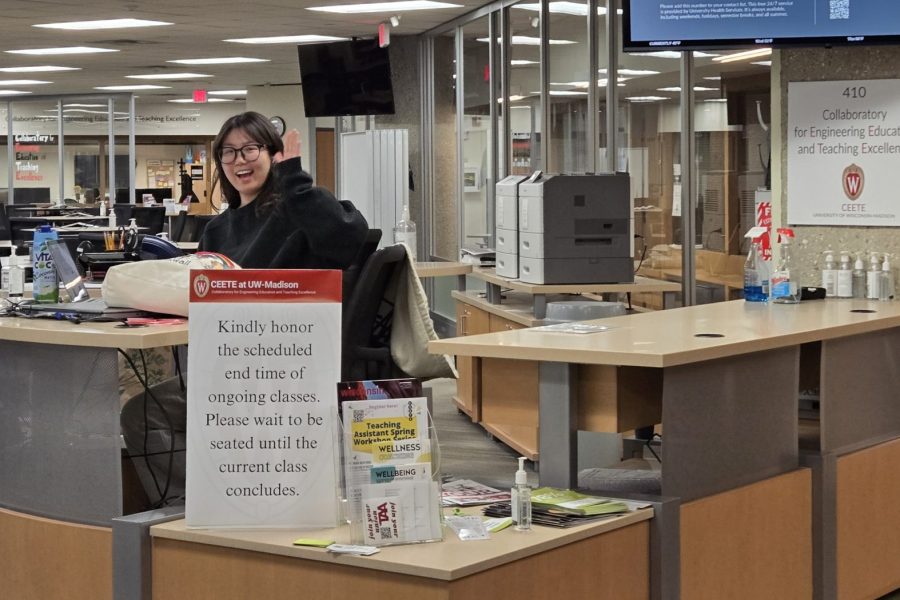 A student staff member waves from behind a welcome desk